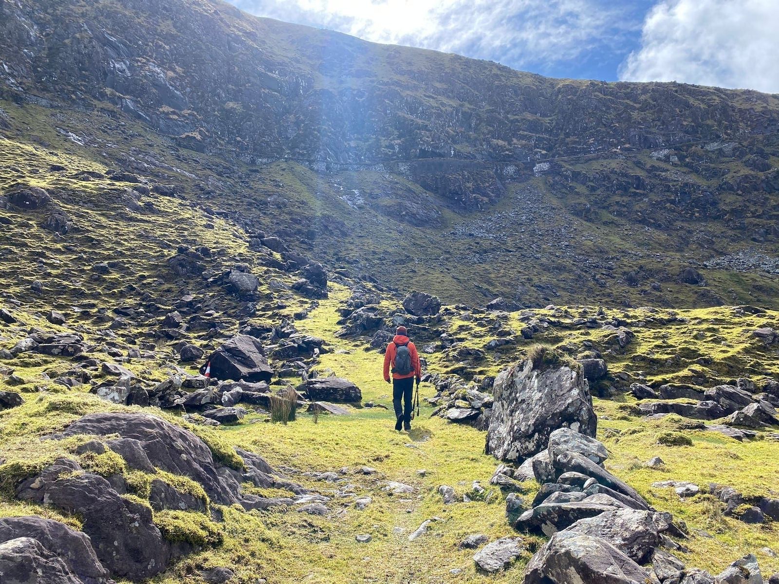 A walker moving through a rocky green hollow on the old route