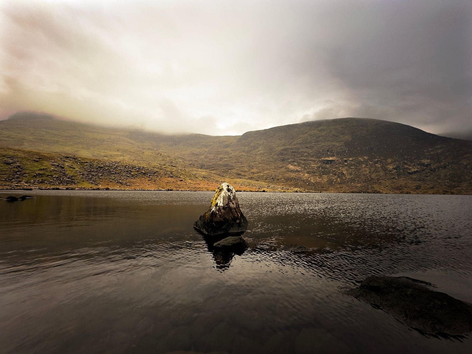 A solitary rock reflected in still mountain water