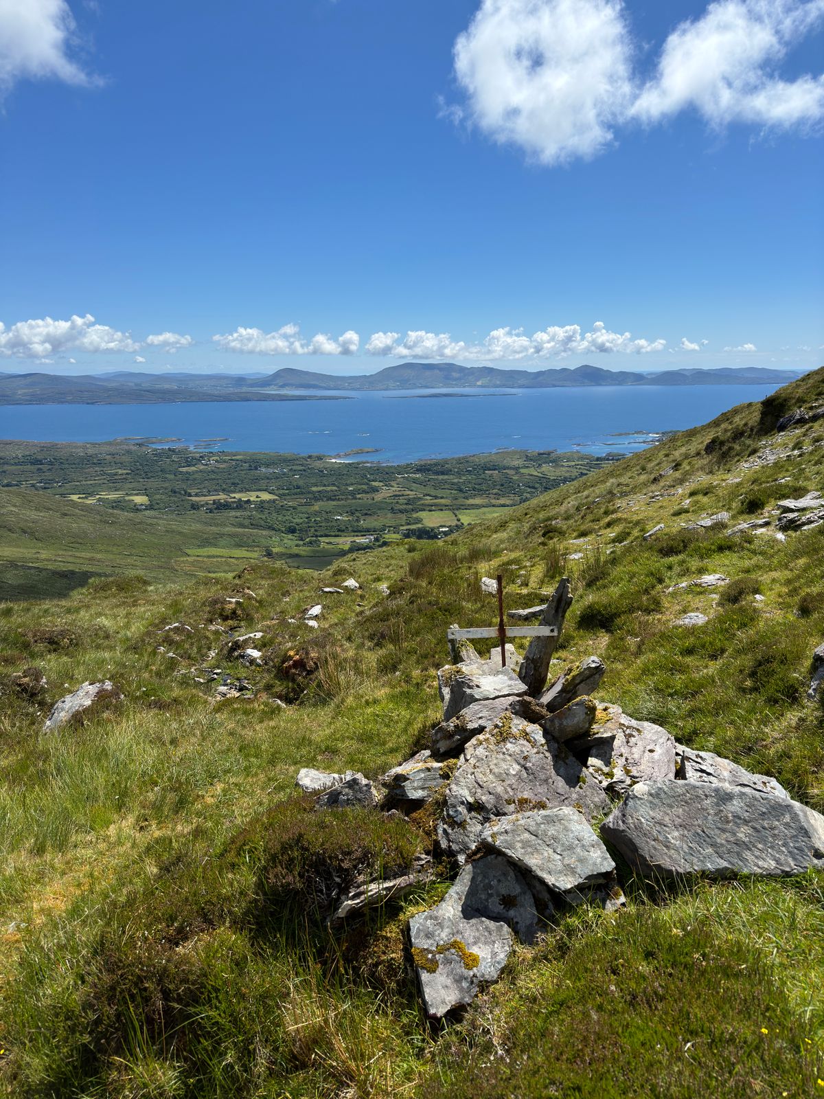 A rocky path descending through grass towards green fields and the sea