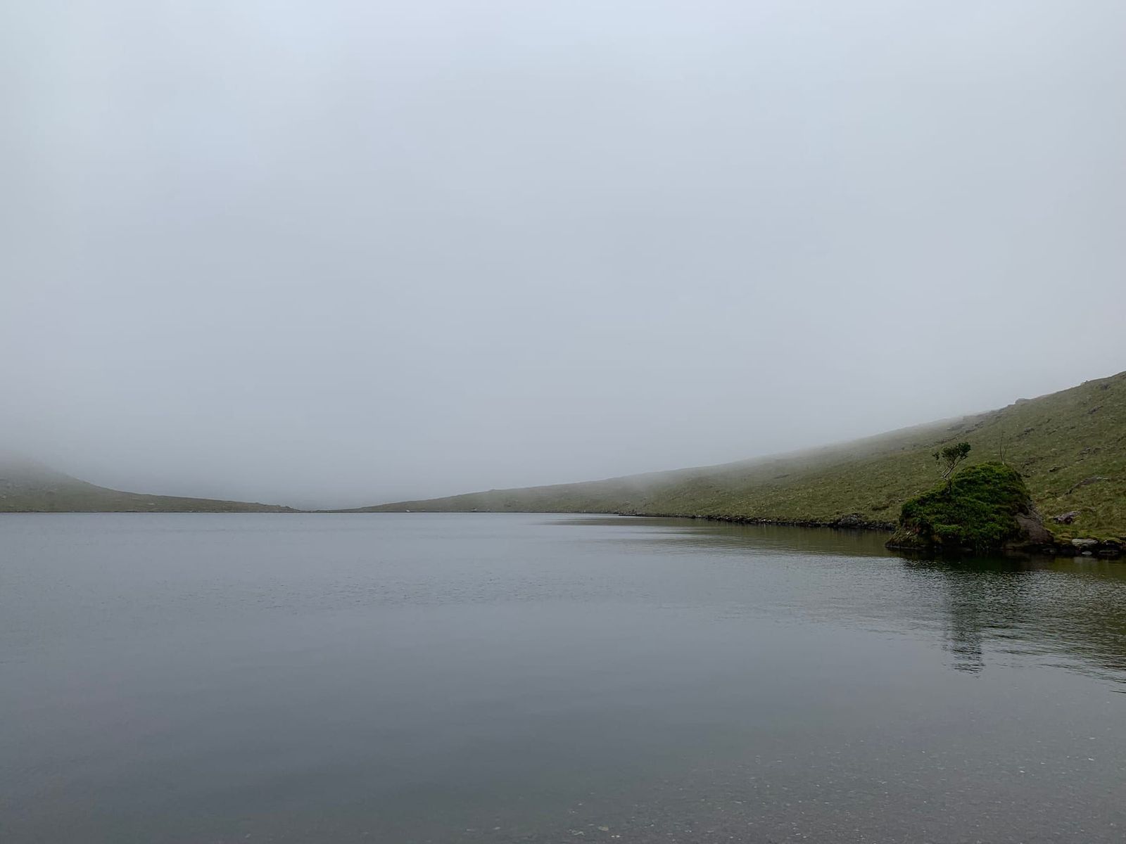 A mountain lough disappearing into low cloud below Carrauntoohil