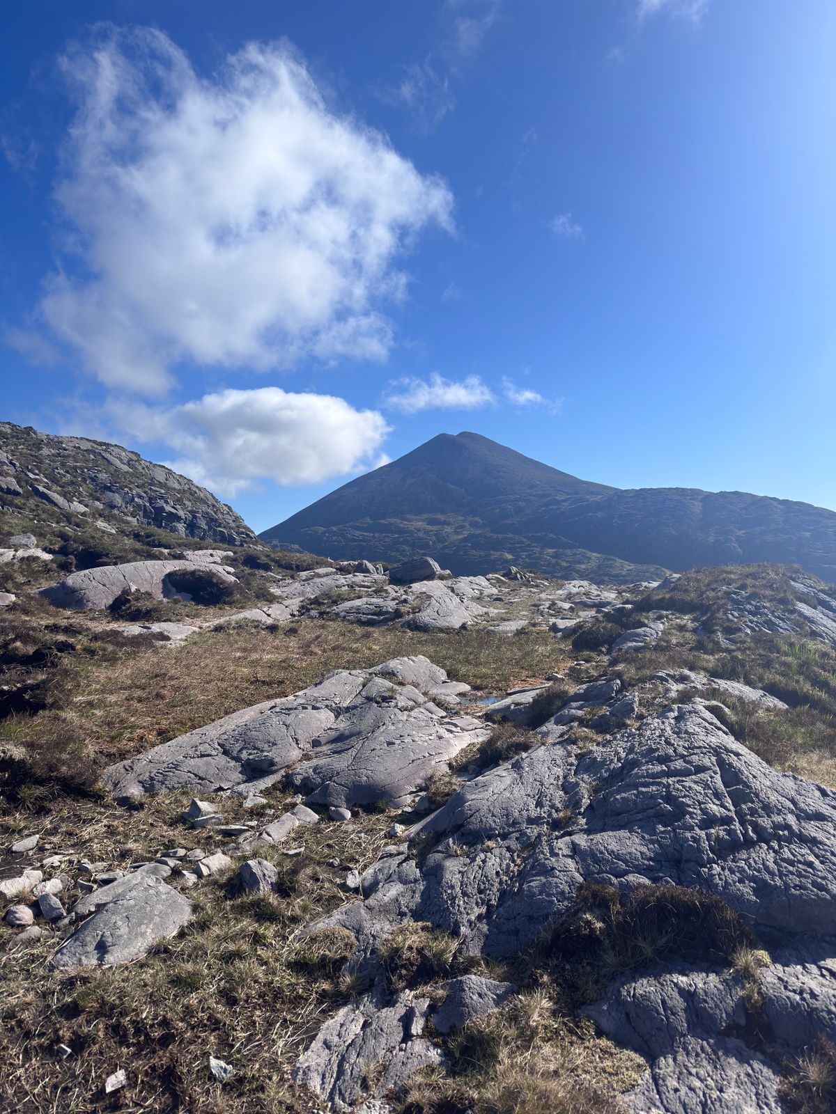 Cnoc na dTarbh seen beyond pale rock under broken cloud