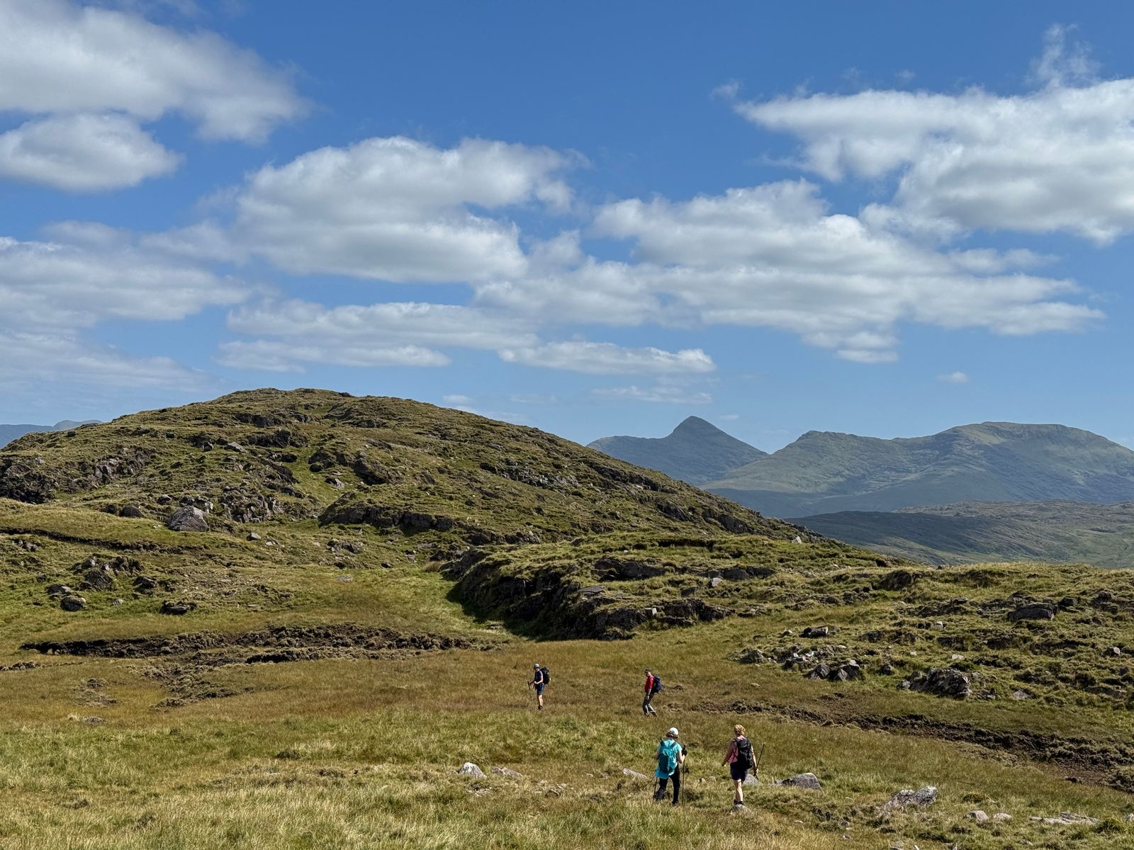 Walkers crossing grassy, rocky ground on the return through Dreenagh