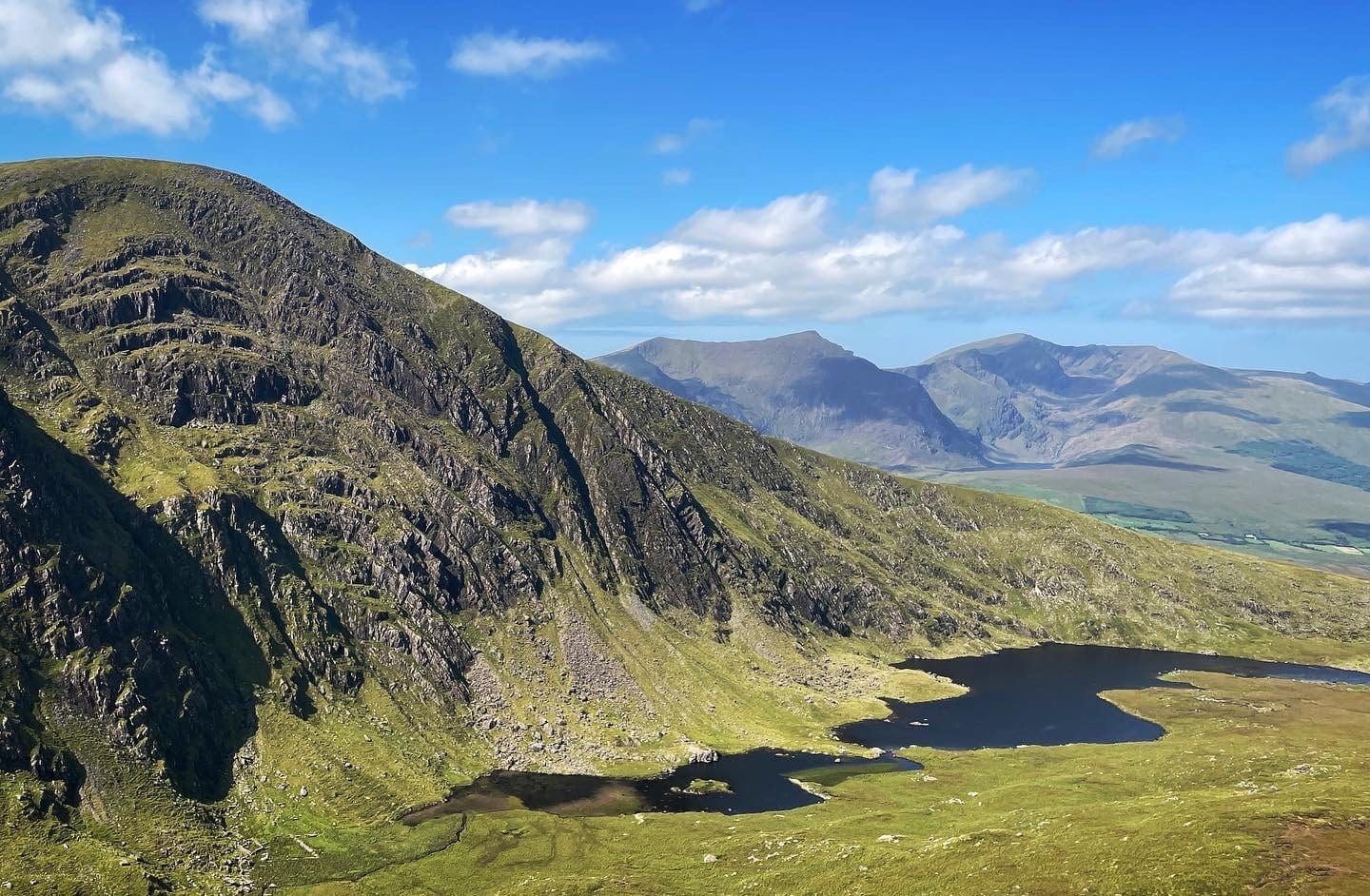 Sunlight picking out the steep cliffs and dark lakes of Com an Áir