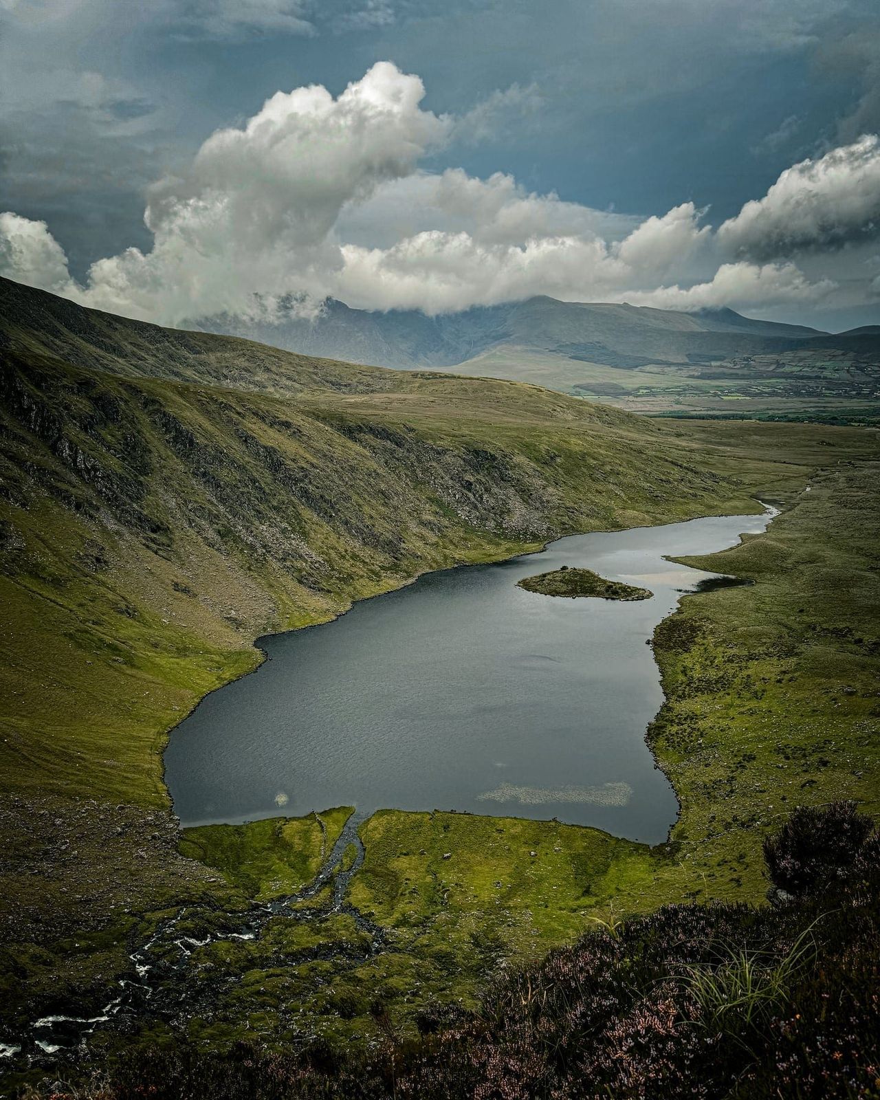 The long dark corrie lake stretching beneath cloud-covered mountain slopes