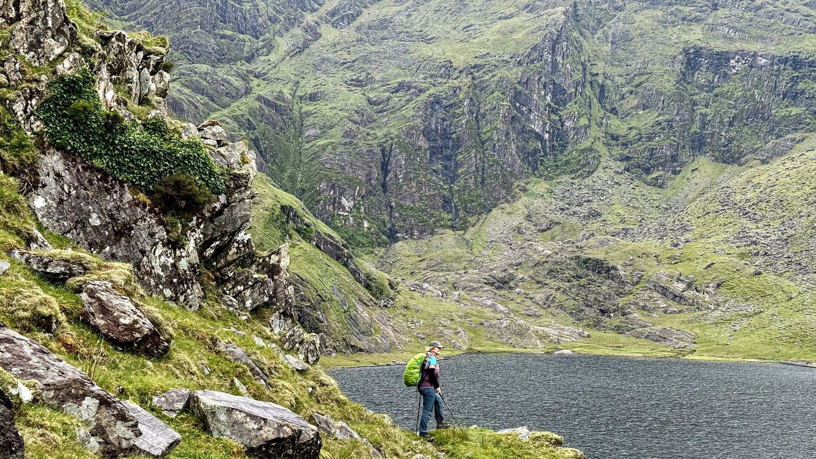 A walker beneath steep corrie cliffs and broken mountain rock