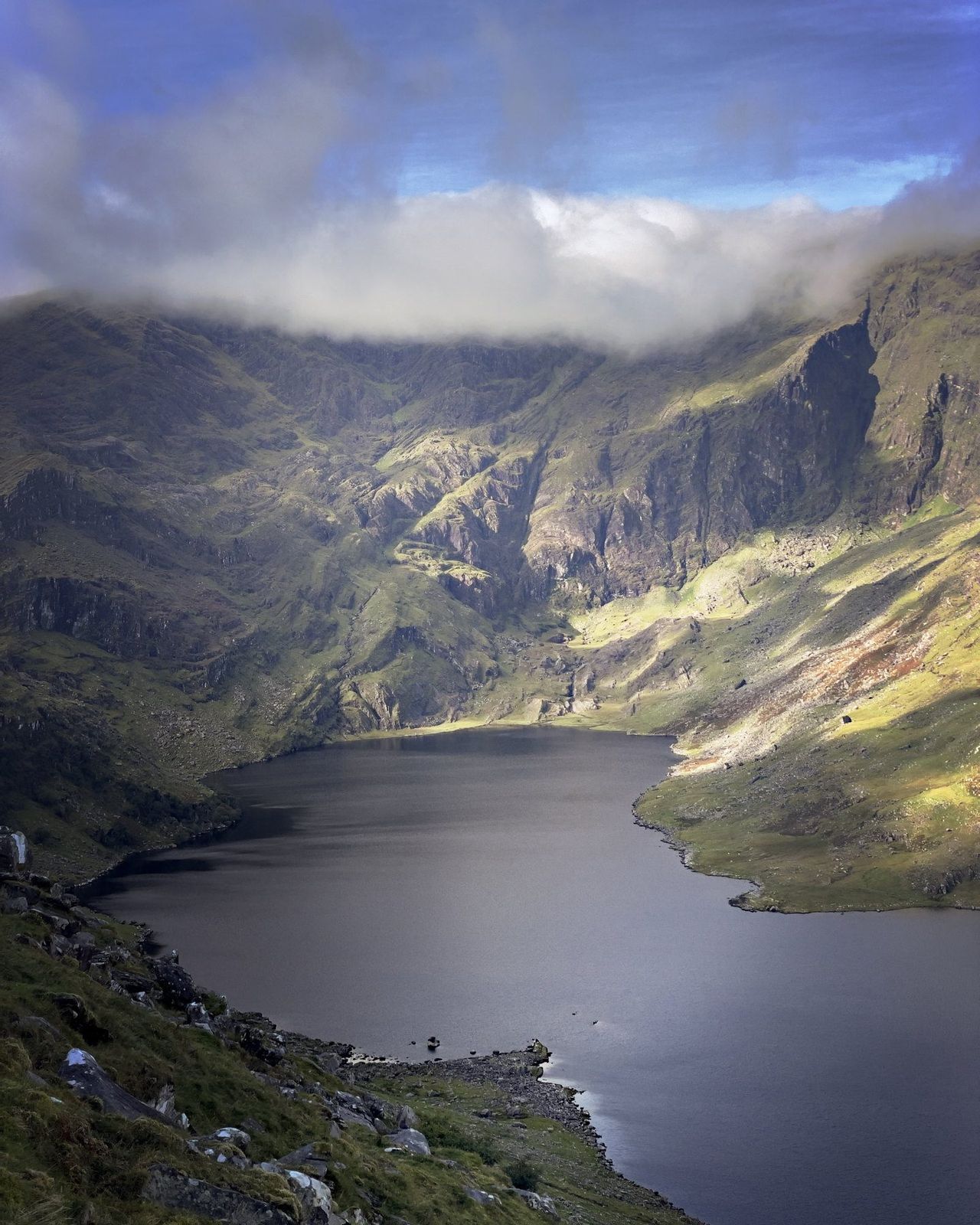 Coomasaharn Lough lit beneath dark cloud and steep corrie walls