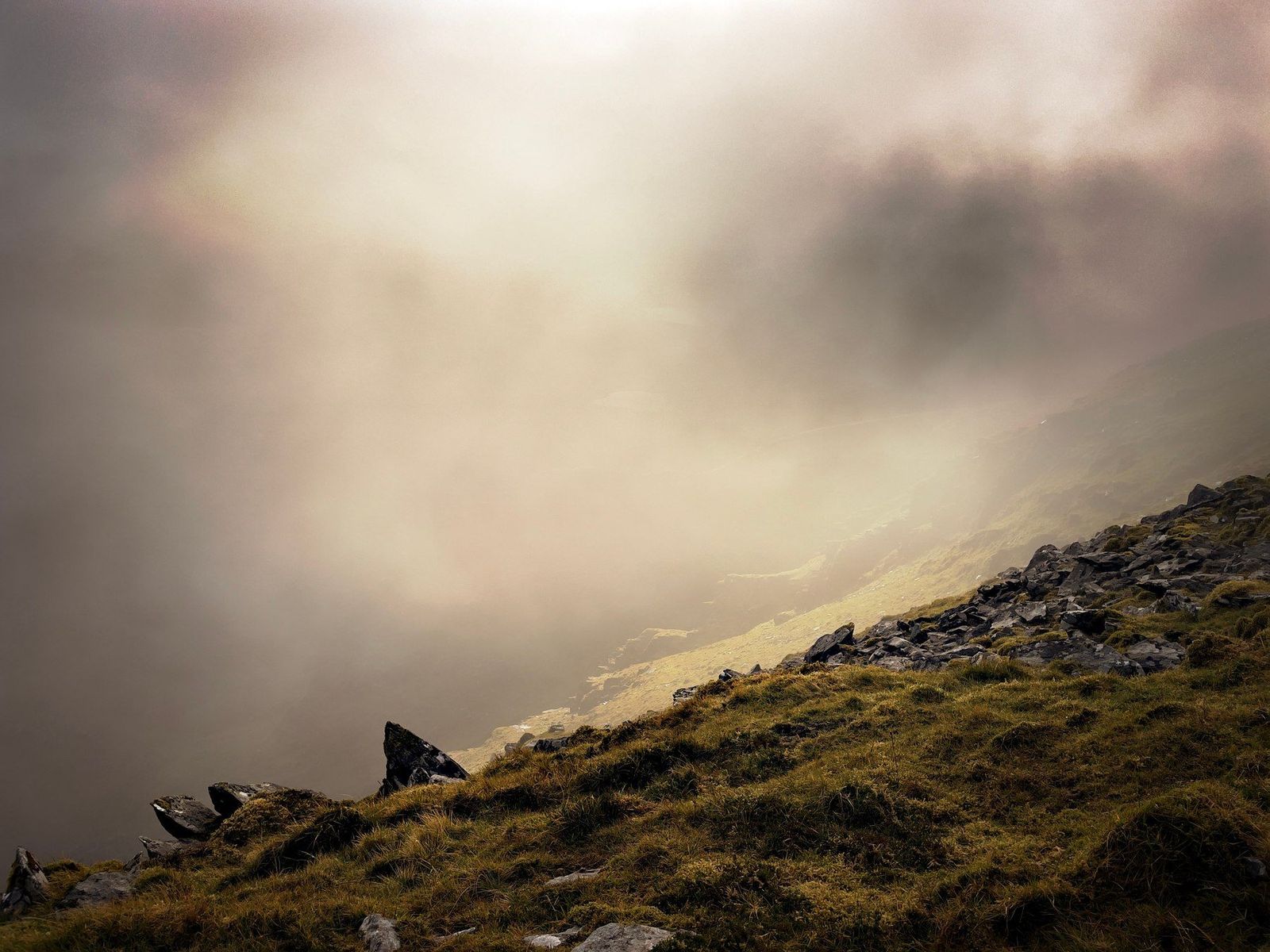 A rocky mountain ridge disappearing into pale mist