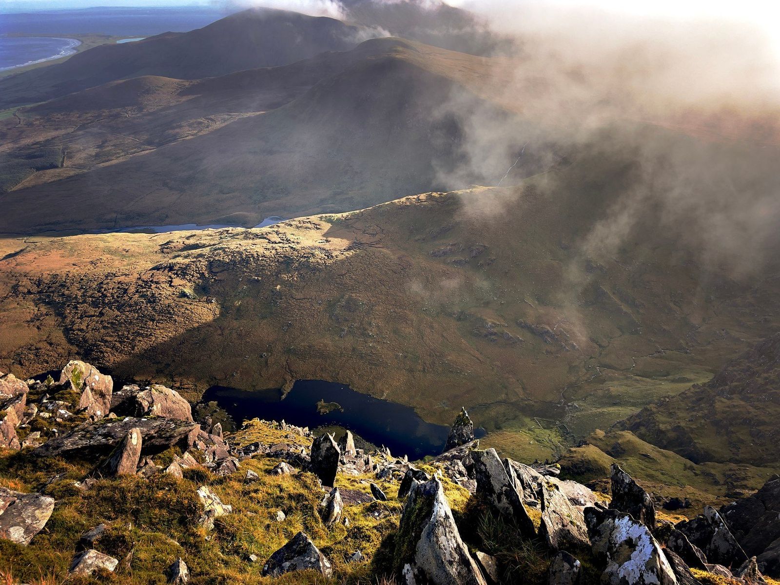 Sunlight breaking through cloud onto a dark corrie and mountain lough