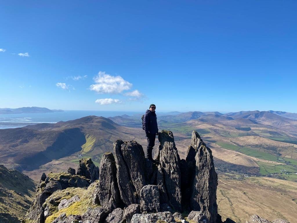 A walker standing among jagged rock pinnacles with mountain country beyond