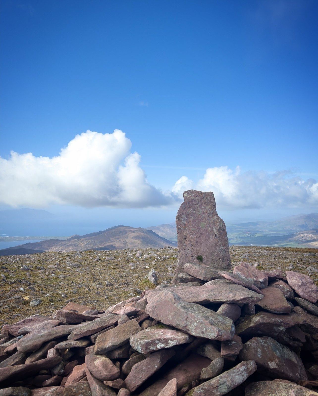A tall weathered stone on high ground beneath a bright Kerry sky