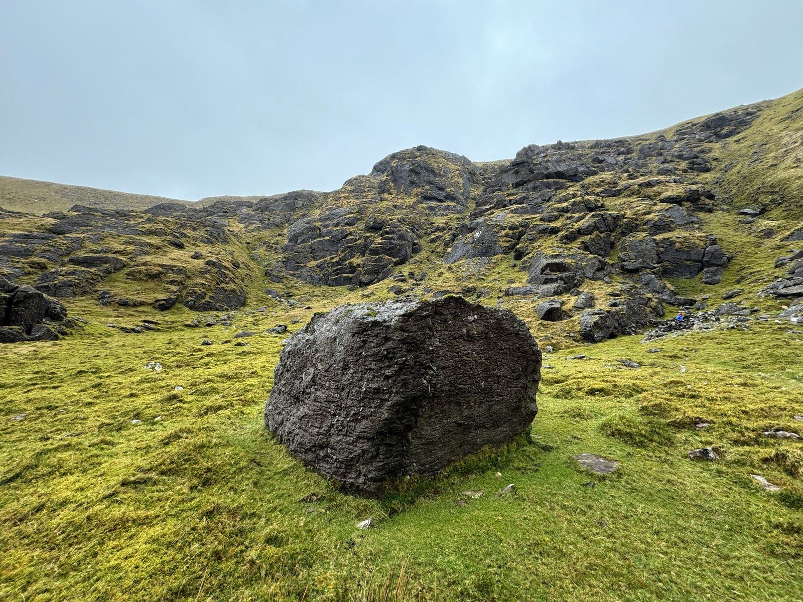 A large rectangular rock standing below the broken cliffs of Derrymore Glen