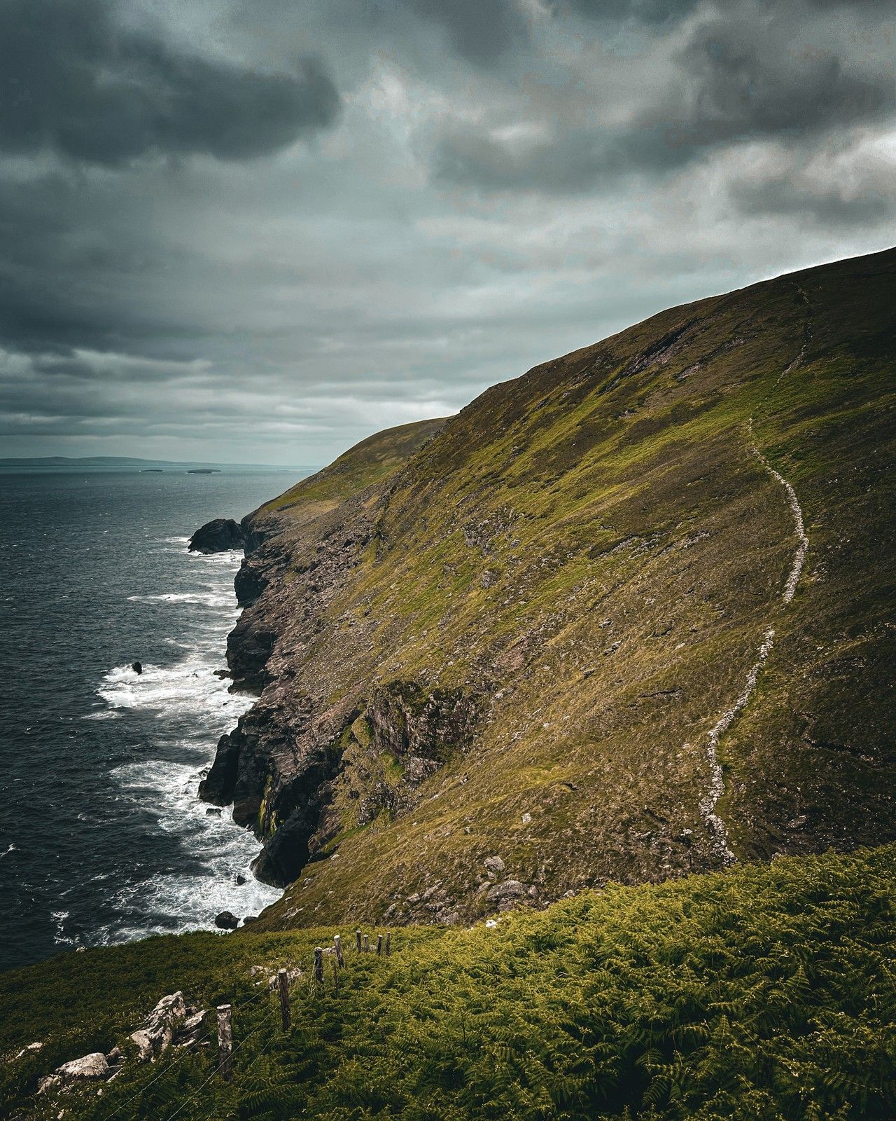 A narrow hillside trail traversing high above Atlantic cliffs near Sás Creek