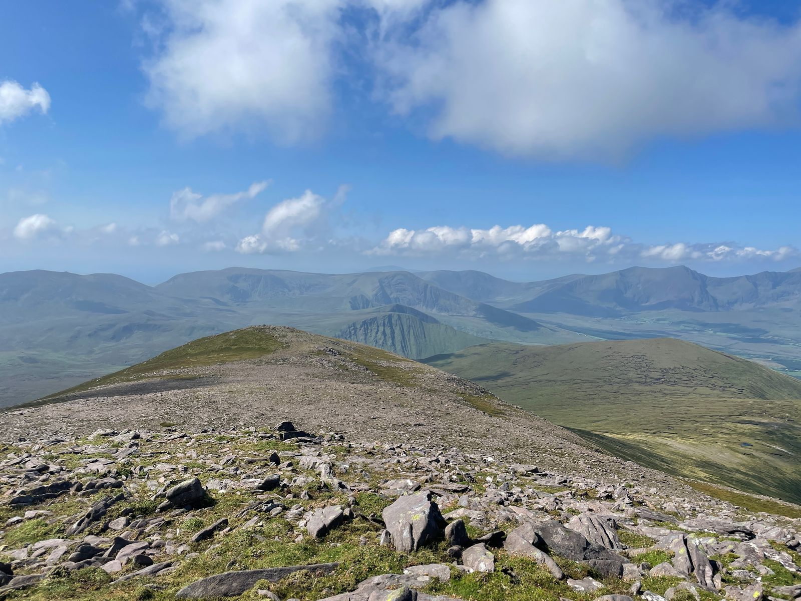 Loose stones on a broad mountain ridge with layered Dingle hills beyond