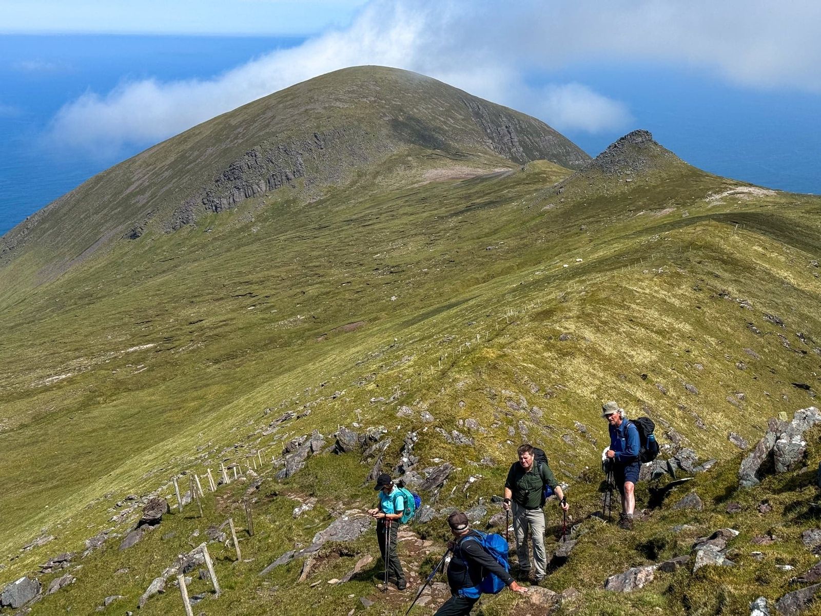 Walkers gathered beneath a rounded Brandon ridge