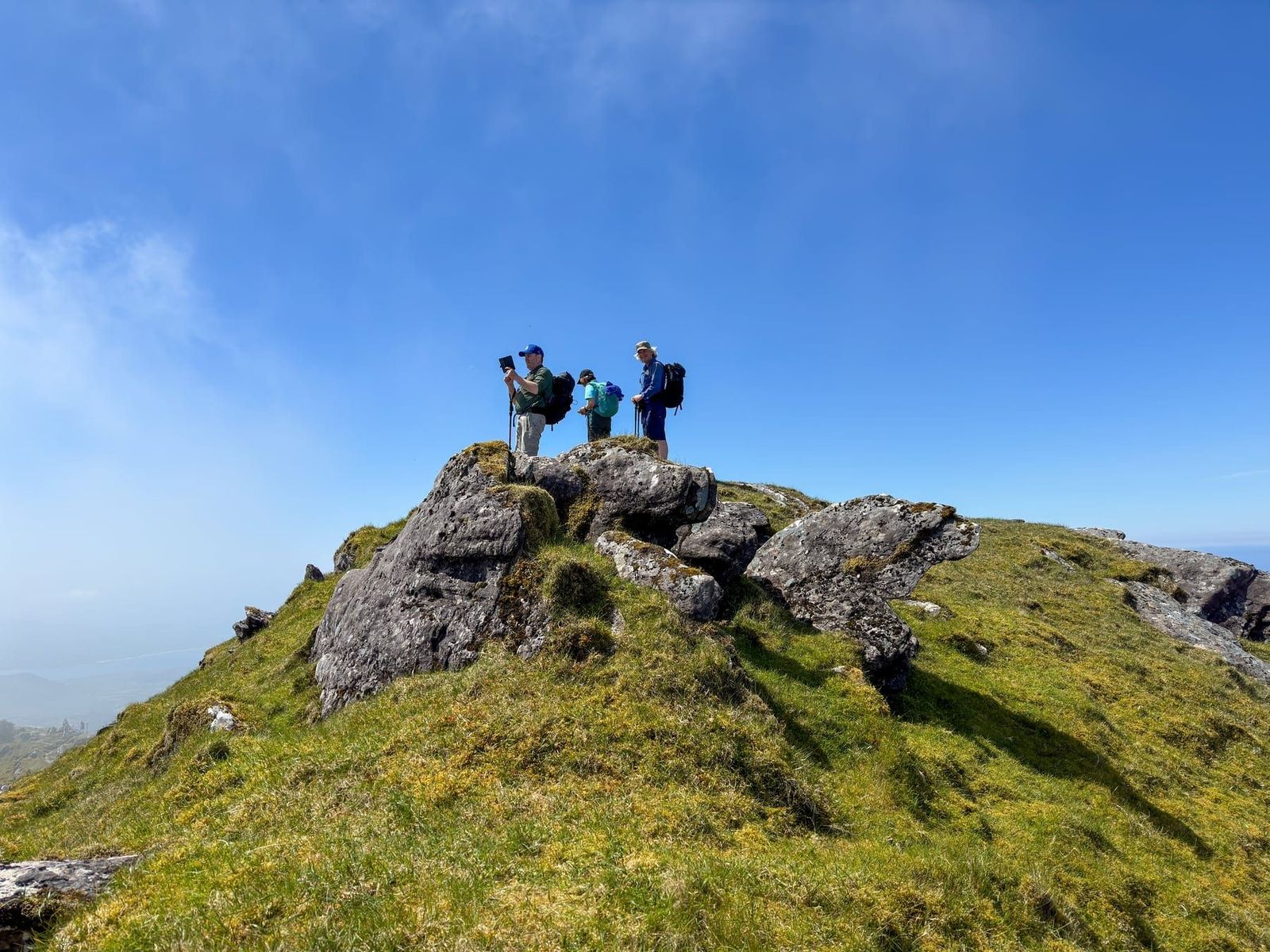 Walkers standing on a rocky outcrop beneath a clear blue sky