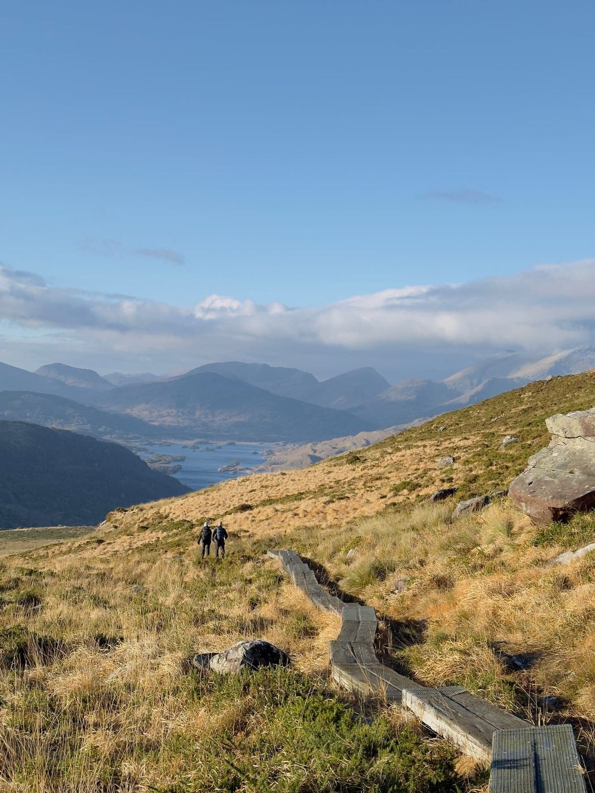 Two walkers descending towards the Killarney lakes in clear weather